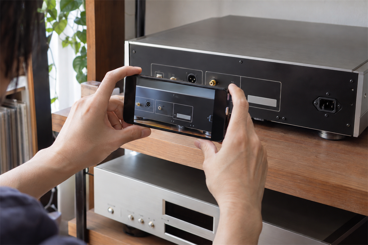 SACD・CDプレーヤー背面の銘板位置をスマートフォンで確認する様子