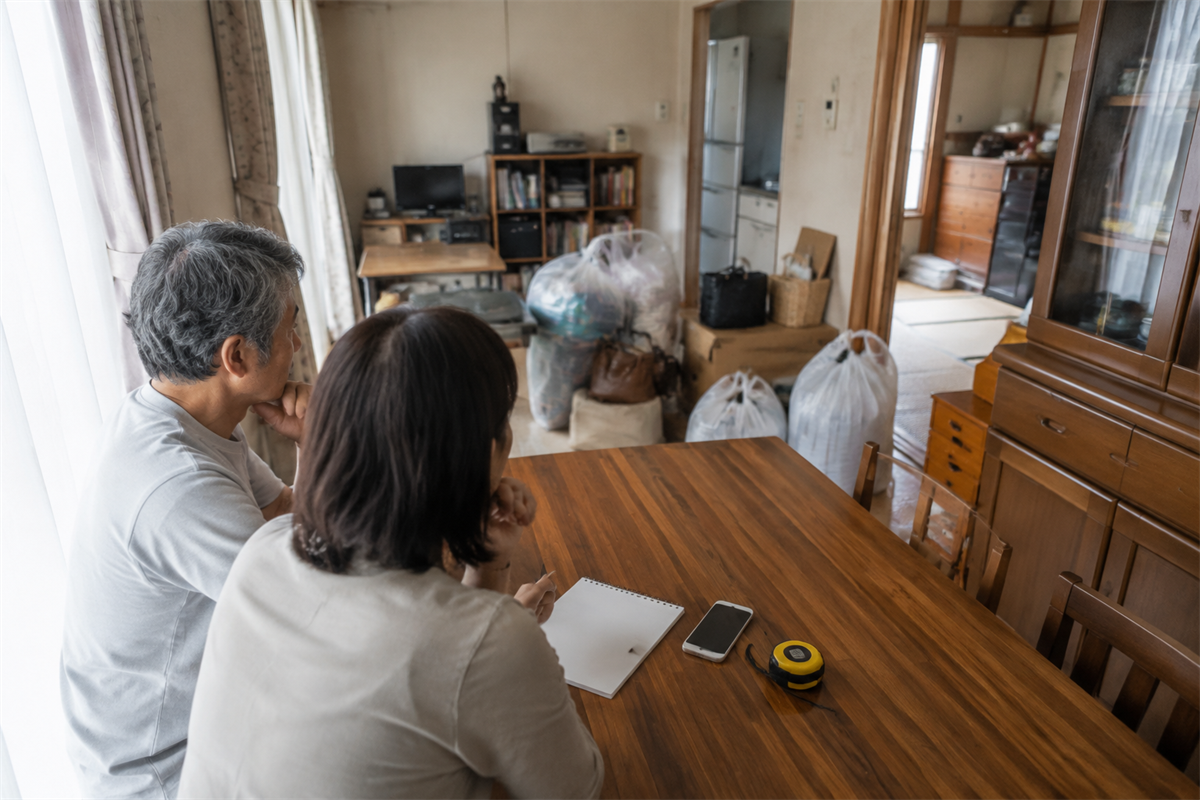 メモとスマートフォンを用意して遺品の量を確認する家族